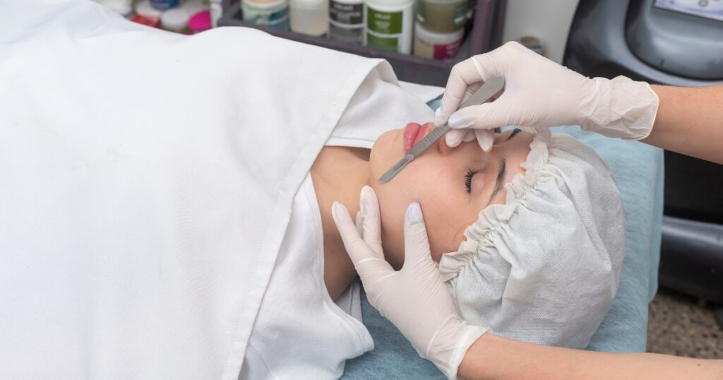 Esthetician performing a derma planing treatment on a client. Example of continuing education for estheticians.